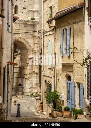 Marches pavées, rue étroite de maisons médiévales, décorées de plantes vertes en pots dans le centre historique d'Arles près de l'amphithéâtre en été. Banque D'Images