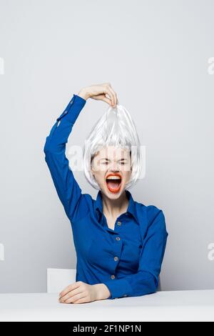 la femme prend la perruque blanche de la tête des émotions assis à boisson de table Banque D'Images