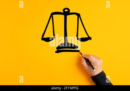 Main masculine dessinant une échelle de justice sur fond jaune. Équité, égalité ou confiance. Banque D'Images