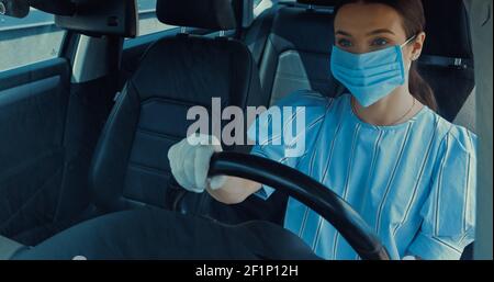 jeune femme dans un masque médical et un gant en latex voiture de conduite Banque D'Images