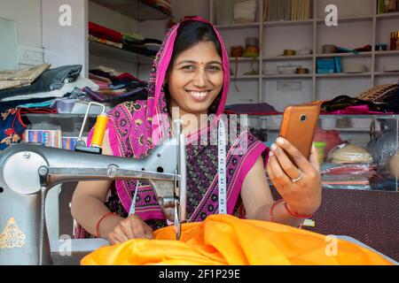 femme indienne tailleur tenant le téléphone mobile à l'atelier Banque D'Images