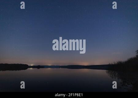 Paysage nocturne avec des étoiles au-dessus d'un lac calme avec espace de copie Banque D'Images