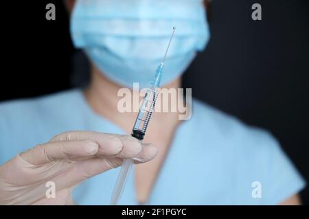 Infirmière avec seringue, femme dans un masque médical et gants de protection se préparant à l'injection. Concept de vaccination pendant la pandémie de Covid-19 Banque D'Images