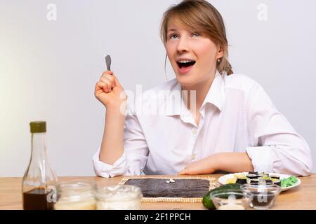 La jeune femme caucasienne fait des sushis à la maison, prenant des cours de cuisine en ligne, flux de nourriture blogging, Internet. Cuisine japonaise asiatique maison Banque D'Images