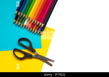 Crayons colorés, ciseaux sur papier et fond blanc. Retour à l'école ou concept d'artisanat Banque D'Images
