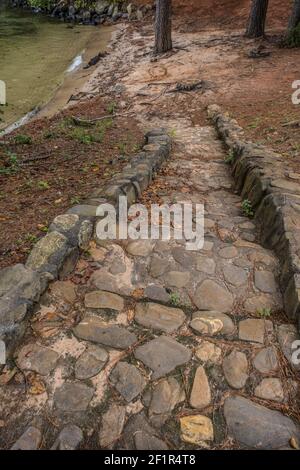 Vieux escalier en pierre et en pierre dans le ciment descendant la descente à la plage au lac avec les bois en arrière-plan au début de l'automne Banque D'Images