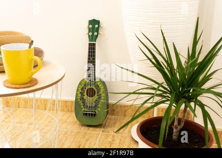 Un ukulele vert avec kiwi peint sur lui dans un séjour ou studio moderne Banque D'Images