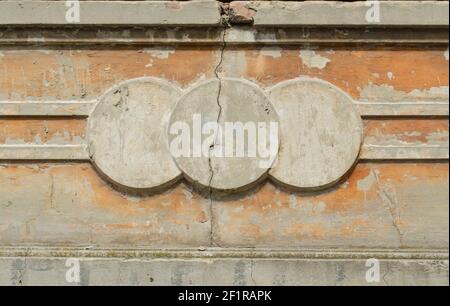 Façade en béton fissuré. Trois cercles de stuc moulés sur la façade beige du bâtiment avec une fissure. Arrière-plan architectural pour Banque D'Images