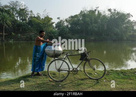 Malda, Inde - janvier 2021: Un homme à côté de son vélo après avoir pris une baignade dans un lac de Malda le 26 janvier 2021 au Bengale occidental, Inde. Banque D'Images