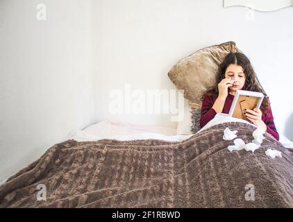 une jeune femme qui pleure avec une photo et des mouchoirs au lit Banque D'Images