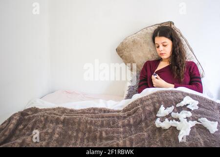 jeune femme malade avec thermomètre allongé dans le lit Banque D'Images