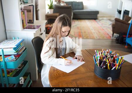 Une jeune fille à une table fait du travail scolaire. Banque D'Images