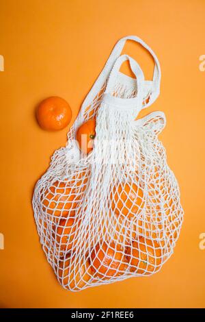mandarines dans un sac de ficelle sur fond orange Banque D'Images