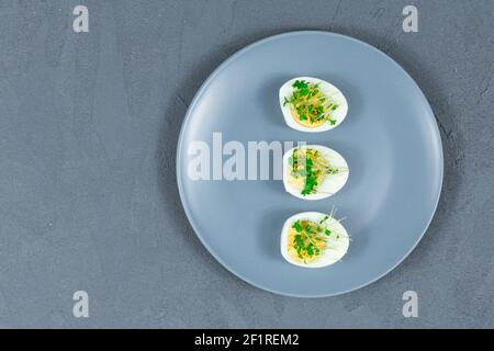 Microgreens sur les œufs. Décorez la salade avec des feuilles micro-vertes. Alimentation. Œufs durs et frais à côté d'herbes fraîches et croustillantes. Salade de style contemporain Banque D'Images