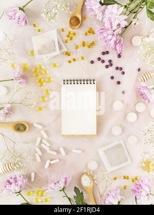 Printemps, composition de soins de santé avec divers types de vitamines, suppléments alimentaires, sachets de tisanes, chrysanthèmes et un carnet. Pose à plat avec nat Banque D'Images