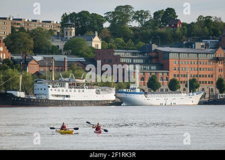 Deux kayakistes traversent Riddarfjarden face de Münchenbryggeriet, Söder Mälarstrand, Södermalm, Stockholm, Suède. Banque D'Images