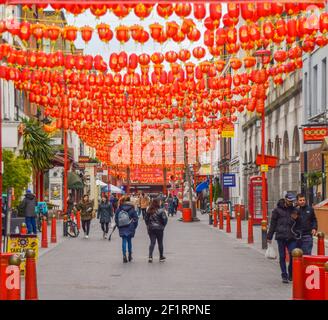 Personnes marchant le long de Gerrard Street dans Chinatown, dans le centre de Londres, décoré de lanternes rouges. Banque D'Images