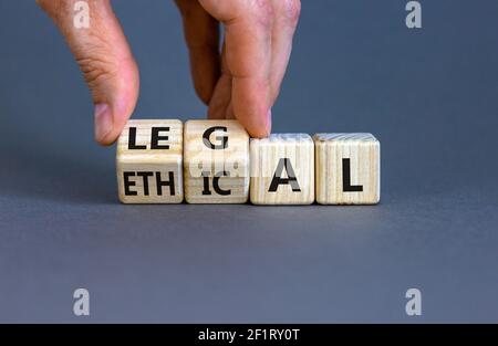 Symbole éthique ou juridique. Homme d'affaires transforme des cubes en bois et change le mot « éthique » en « juridique » sur une belle table grise, fond gris. Entreprise Banque D'Images