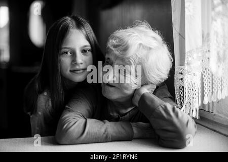 Une petite fille embrasse sa grand-mère. Portrait en noir et blanc. Banque D'Images