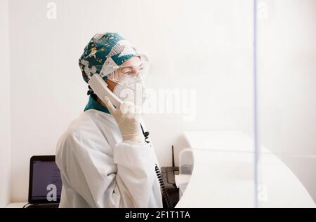 infirmière avec équipement de protection personnel et téléphone en mains, réception à l'hôpital dentaire Banque D'Images