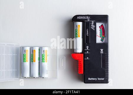 Un testeur de batterie en plastique noir avec une pince sur le côté où différents types de batteries peuvent être insérés afin de mesurer leur niveau de charge. Banque D'Images