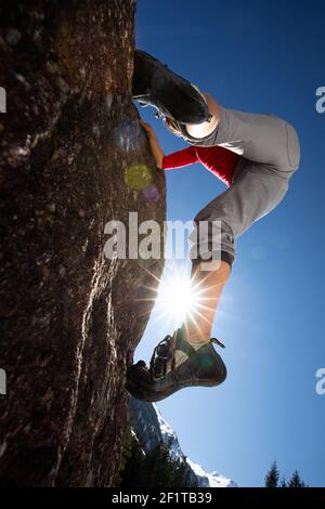 Jeune femme grimpeur mettant des chaussures d'escalade avant d'escalader un rocher en plein air, dans les Alpes suisses Banque D'Images