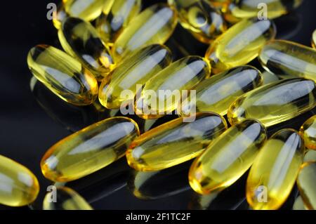 Gros plan des capsules huile de poisson sur fond noir. Oméga 3. Vitamine E. Banque D'Images