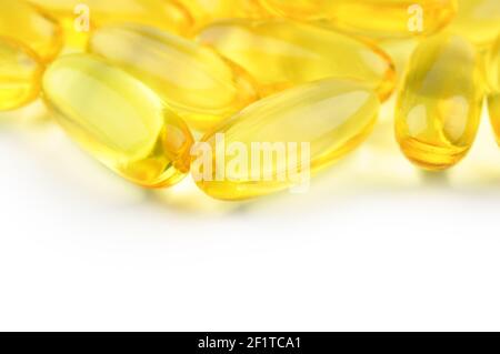 Capsules huile de poisson isolée sur fond blanc et beaucoup d'autres capsules sur fond flou. Concept de soins de santé. Banque D'Images