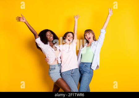 Photo de Nice optimiste trois femmes embrasse les bras vers le haut jean blanc avec chemise isolée sur fond jaune vif Banque D'Images