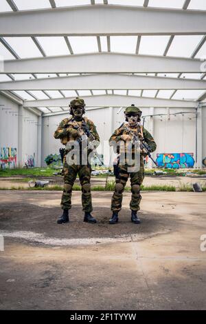 Deux soldats entièrement équipés posant avec des fusils d'assaut dans un zone couverte Banque D'Images