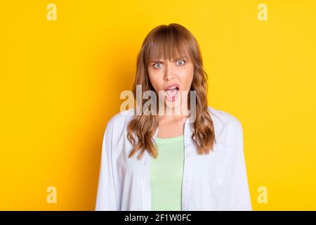 Portrait d'une femme impressionnée et imsatisfaite qui se fait voir avec un appareil photo à la bouche ouverte fort isolé sur fond jaune Banque D'Images