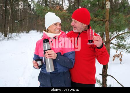 Le couple boit des boissons chaudes au parc d'hiver Banque D'Images