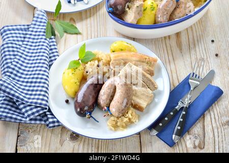 Assiette de viande et de saucisse bavaroises avec pudding et saucisses fraîches, ventre de porc, pommes de terre bouillies et choucroute Banque D'Images