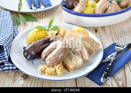 Assiette de viande et de saucisse bavaroises avec pudding et saucisses fraîches, ventre de porc, pommes de terre bouillies et choucroute Banque D'Images