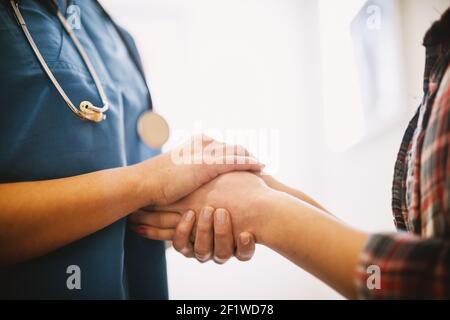 Vue portrait rapprochée d'une infirmière professionnelle d'âge moyen tenant les mains d'un patient. Banque D'Images