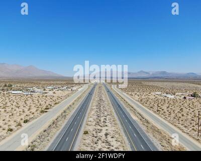 Vue aérienne de la route au milieu du désert sous un ciel bleu dans le désert de Mojave en Californie, près de Ridgecrest. Banque D'Images