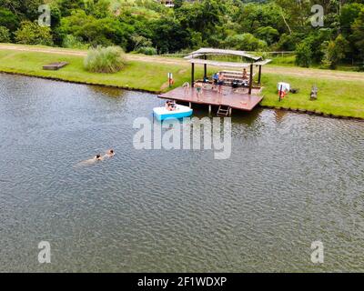 Vue aérienne de la petite cabana en bois sur le lac dans la vallée verdoyante, avec la famille en appréciant un moment de détente Banque D'Images