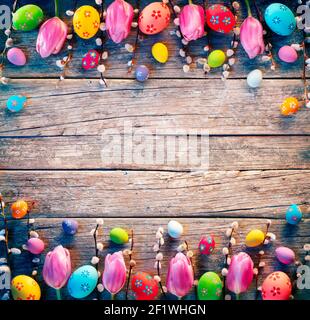 Décoration de Pâques vintage - oeufs peints avec branches de Willows et Tulipes sur table rustique Banque D'Images