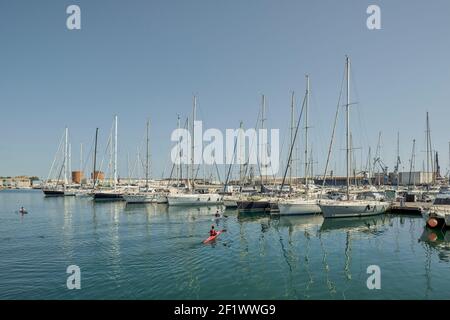 Kayakistes du véritable club nautico naviguant dans leurs canoës rouges à travers les eaux du Grao de Castellon, avec les yachts en arrière-plan, Espagne Banque D'Images