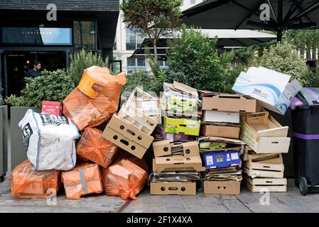 Pile de déchets, y compris carton et boîtes de fruits en bois empilées Devant le Lighterman Restaurant Granary Square, qui attend la collection Kings Croix Banque D'Images