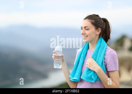 Jogger heureux tenant une bouteille d'eau contemplant la vue après sport en montagne Banque D'Images