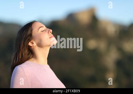 Femme détendue respirant de l'air frais dans la montagne avec un chaud léger Banque D'Images