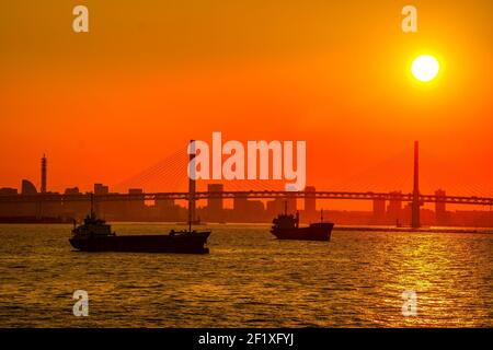 Silhouette de cargo et coucher de soleil sur les gratte-ciel de Yokohama Banque D'Images