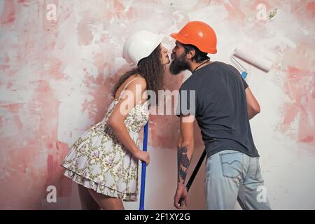 Couple de famille travaillant et répare. Builder man baiser fille dans un casque avec outil. Bâtiment et construction. Homme et femme en casque. Banque D'Images