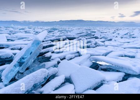 Un champ d'hummock sans fin sur le lac Baïkal gelé. Des tas de débris de glace bleue couverts de neige par temps gelé. Arrière-plan froid et naturel. Un hiver inhabituel Banque D'Images