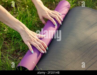Femme pliant tapis d'exercice avant ou après l'entraînement le parc Banque D'Images