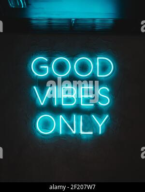Un néon bleu sur un mur avec des mots ''bonnes vibrations uniquement'' Banque D'Images