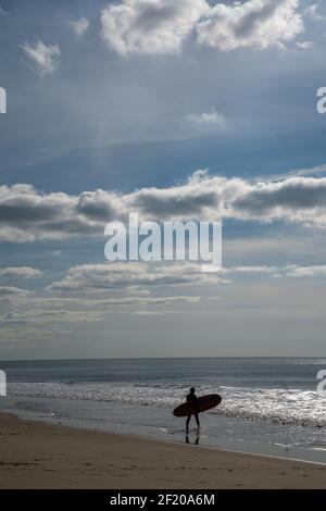 Un surfeur mâle entre dans l'océan Atlantique sur le Côte d'argent pour attraper quelques vagues Banque D'Images