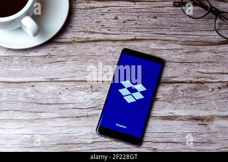 Un téléphone portable ou mobile posé sur un bois Table ou bureau avec l'application Dropbox ouverte Banque D'Images