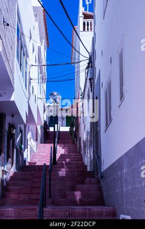 Vue sur un escalier en pierres roses avec une rambarde au milieu. À droite et à gauche, bordée de bâtiments Banque D'Images